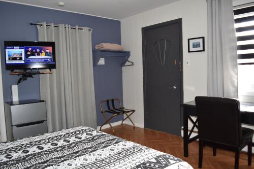 a bedroom with a bed and a desk and a television at Motel de L'Anse et Camping Rimouski in Rimouski