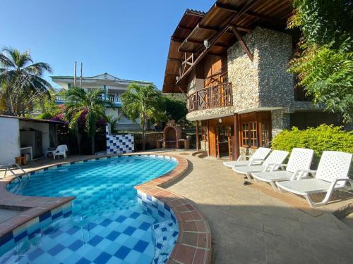 una piscina con sillas blancas y una casa en Cabana Dubai Resorts, en Santa Verónica