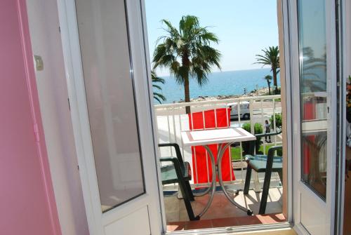 a balcony with a table and chairs and the ocean at Hôtel Azur in Nice