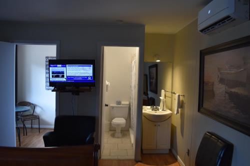 a room with a bathroom with a television and a sink at Motel de L'Anse et Camping Rimouski in Rimouski