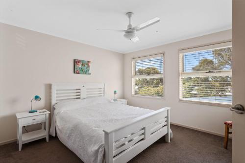 a bedroom with a white bed and two windows at 45 Norman Drive in Cowes