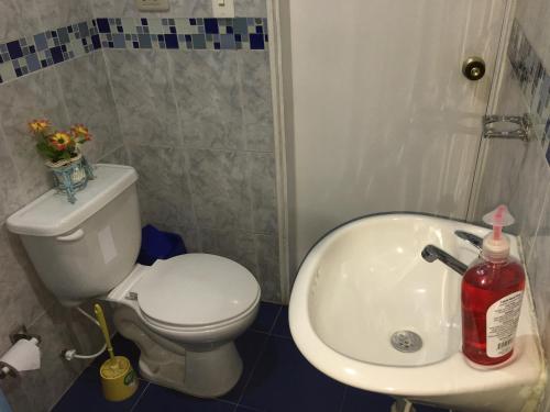 a bathroom with a white toilet and a sink at Dorado Airport rooms & apartments in Bogotá