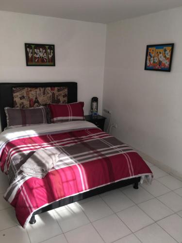 a bedroom with a bed with a pink and black comforter at Dorado Airport rooms & apartments in Bogotá