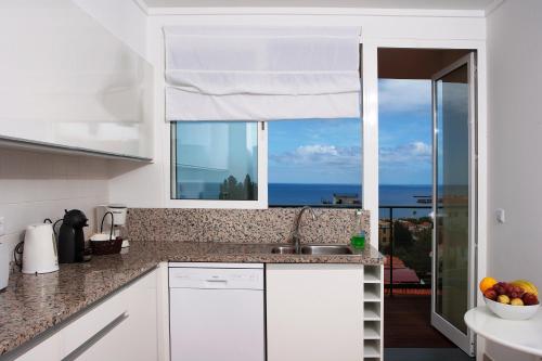a kitchen with a sink and a window with the ocean at Carvalhal Old Town in Funchal
