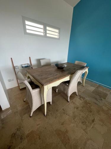 a dining room table with wicker chairs and a wooden table at Le Lantana by EGL IMMO in Le Marin