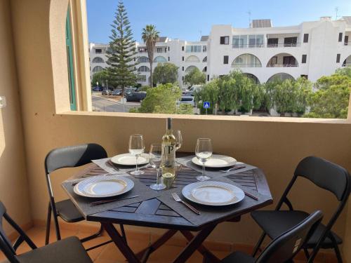 a table with chairs and wine glasses and a window at Casa dos Salgados in Albufeira