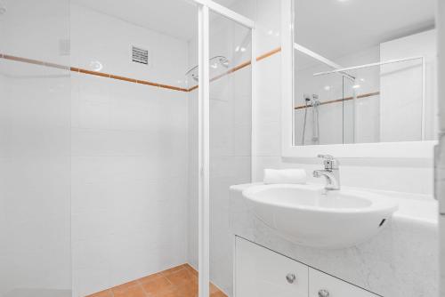bagno bianco con lavandino e specchio di The Rocks Resort Unit 2i a Gold Coast