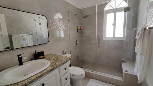 een badkamer met een wastafel, een toilet en een douche bij Luxury 4-Bedroom Villa with Heated Pool in Residencial Casa Linda in Sosúa