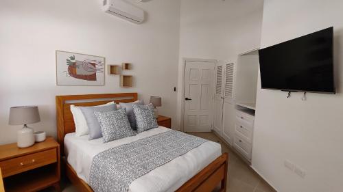 een slaapkamer met een bed en een flatscreen-tv bij Luxury 4-Bedroom Villa with Heated Pool in Residencial Casa Linda in Sosúa