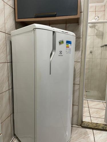 a white refrigerator sitting in a kitchen next to a wall at Kit Net Santa Cruz in Praia Grande