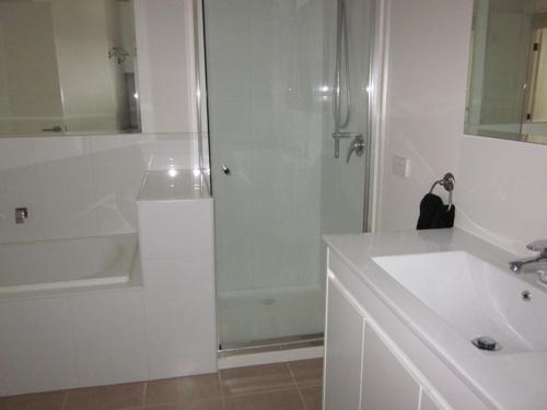 uma casa de banho branca com um chuveiro e um lavatório. em Red Rocks Getaway em Cowes