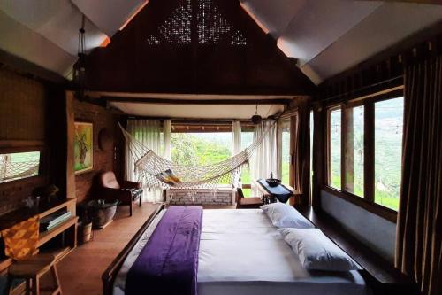 a large bed in a room with a hammock at Villa Cetok Syariah - Nuansa Pedesaan in Simpen