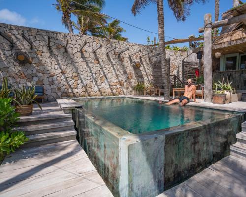 un uomo è seduto in una piscina di Ahau Tulum - Beachfront Hotel a Tulum