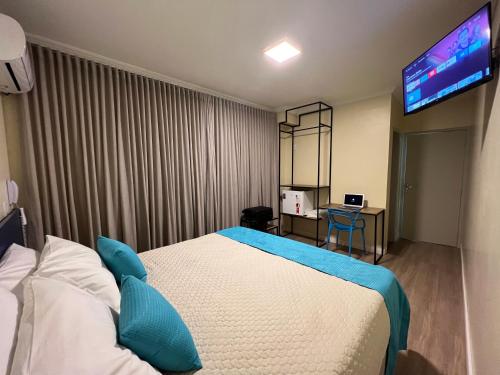 a hotel room with a bed and a flat screen tv at Hotel Suntuoso in Brasilia