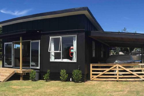 a black house with a fence in front of it at Black Beauty - Spacious Family Retreat for 12 with Spa in Mangakino