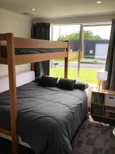 a bedroom with a bunk bed and a large window at Black Beauty - Spacious Family Retreat for 12 with Spa in Mangakino