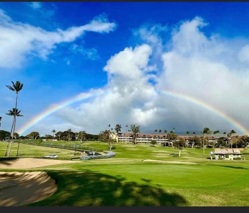 a rainbow over a golf course with a green at Kaanapali's Royal Luxury Plantation Beach & Golf Retreat in Kaanapali