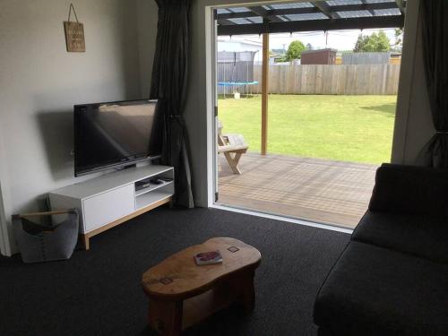 a living room with a flat screen tv and a wooden porch at Black Beauty - Spacious Family Retreat for 12 with Spa in Mangakino