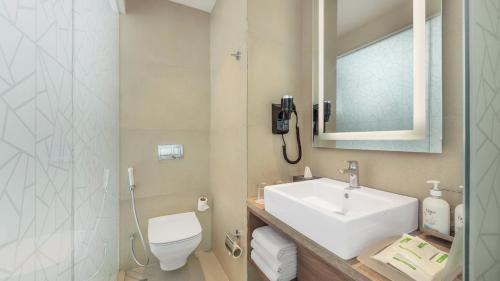 a bathroom with a sink and a toilet and a mirror at Holiday Inn Gurugram Sector 90 by IHG in Gurgaon
