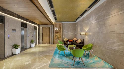 a lobby with green chairs and a table at Holiday Inn Gurugram Sector 90 by IHG in Gurgaon