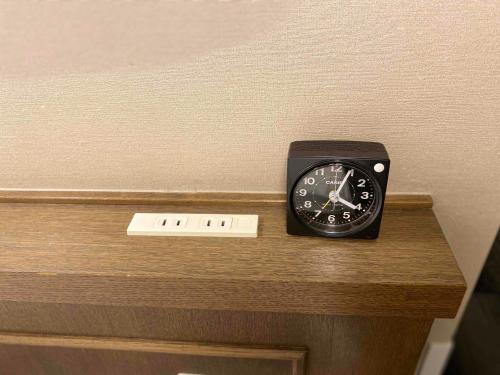 a black clock sitting on top of a wooden shelf at Smile Hotel Nagano in Nagano