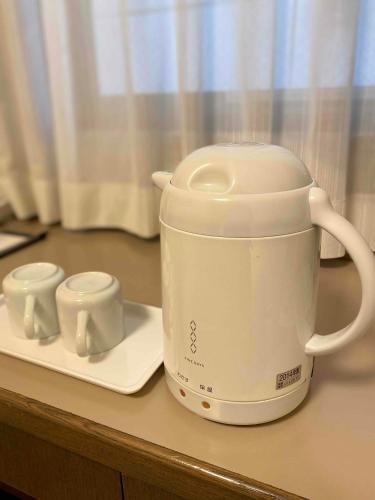 a white toaster sitting on a counter with two cups at Smile Hotel Nagano in Nagano