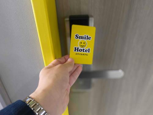 a person holding a yellow card in front of a door at Smile Hotel Nagano in Nagano