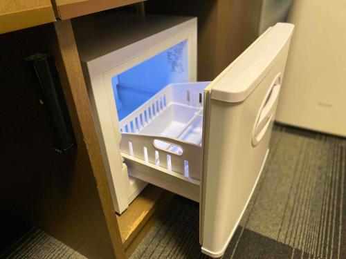 a small refrigerator with its door open in a kitchen at Smile Hotel Nagano in Nagano