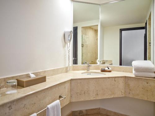 een badkamer met een wastafel en een spiegel bij Fiesta Inn Toluca Centro in Toluca