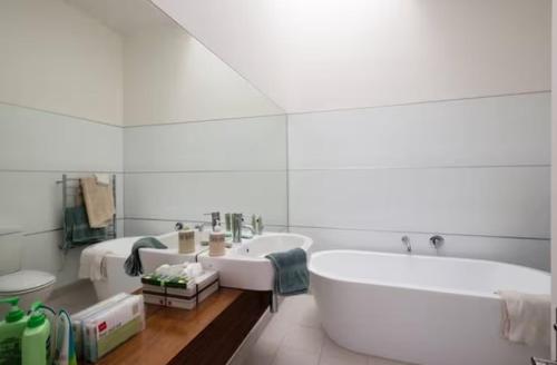 ein weißes Badezimmer mit einer Badewanne und einem Waschbecken in der Unterkunft Kelburn House at the top of the Cable Car in Wellington