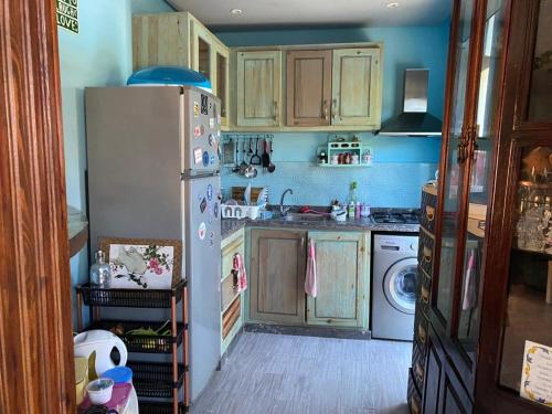 a kitchen with wooden cabinets and a white refrigerator at Maison du bonheur in El Harhoura