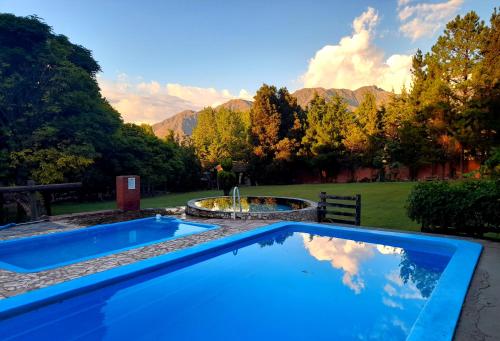 a swimming pool with a fountain and mountains in the background at Cabaña Suiza in Cacheuta