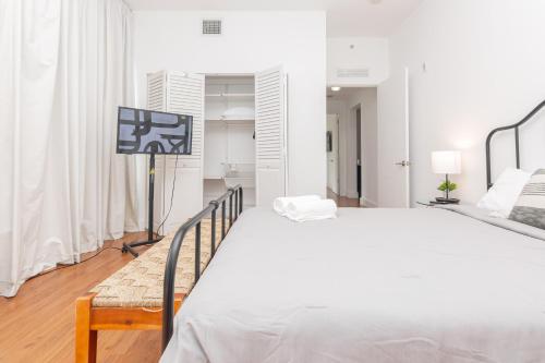 a white bedroom with a large bed and a television at Miami Downtown 2 Bedrooms Apartment - 10 minutes to Beach - 5 minutes to Wynwood in Miami