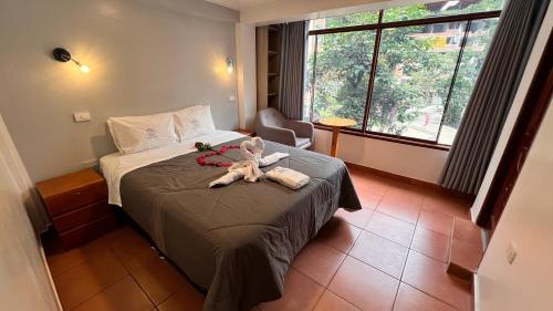 a bedroom with a teddy bear sitting on a bed at QUECHUA´S HOUSE Hostal & Coffee in Machu Picchu