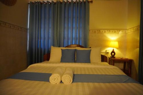 a bedroom with a large bed with blue curtains at Le Tonle in Kratie