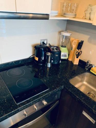 a kitchen counter with a stove and a sink at Las Condes, al lado de Marriott y Parque Arauco, ideal para Trabajo, Salud y Vacaciones in Santiago