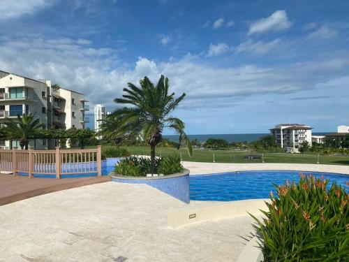 una palmera sentada junto a una piscina en Lujoso y Familiar Apartamento de Playa y Golf en San Carlos Panamá, en San Carlos