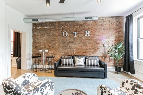 a living room with a black couch and a brick wall at Urban Paradise in OTR - Beautiful New Condo In Historic Building With Downtown Views! condo in Cincinnati