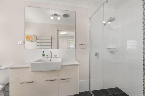 a white bathroom with a sink and a shower at Government Rd 77 Shoal Bay in Shoal Bay
