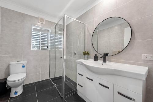 y baño con aseo, lavabo y espejo. en Sea Breeze Two Bedroom Apartment, en Redcliffe