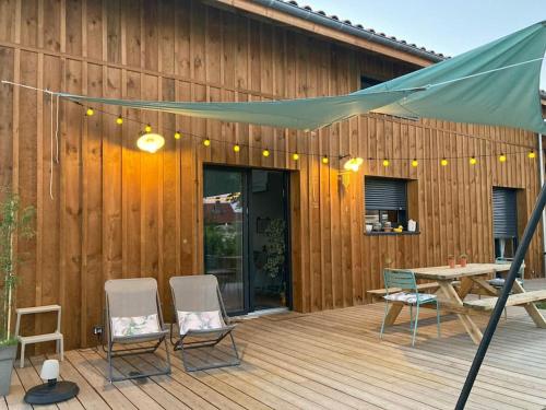 une terrasse avec des chaises, une table et une tente dans l'établissement Belle villa neuve bioclimatique proche plages golf, à Seignosse