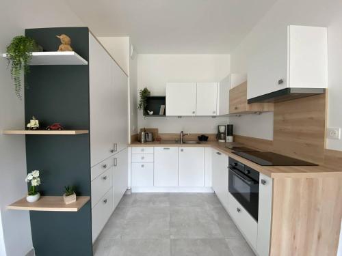 une cuisine avec des armoires blanches et un four à plaques de cuisson dans l'établissement Appartement neuf avec balcon, proche du port de Perros-Guirec - FR-1-368-392, à Perros-Guirec