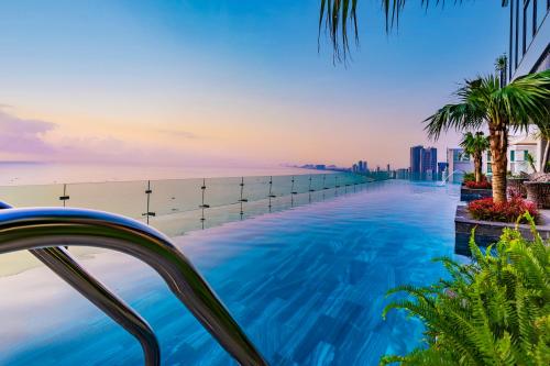a swimming pool with a view of the ocean at Peninsula Hotel Danang in Da Nang