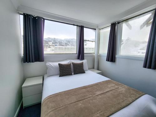 a small bedroom with a bed and two windows at Lodge 21 in Perisher Valley