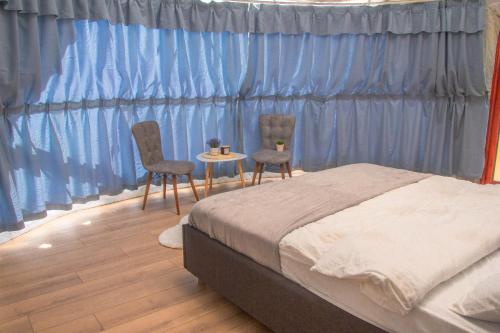 a bedroom with a bed and two chairs and a table at Sanctum Glamping in Jupâneşti