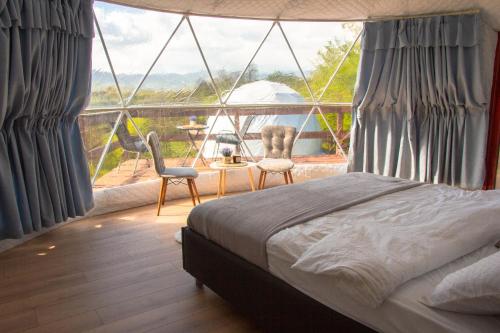 a bedroom with a bed and a large window at Sanctum Glamping 