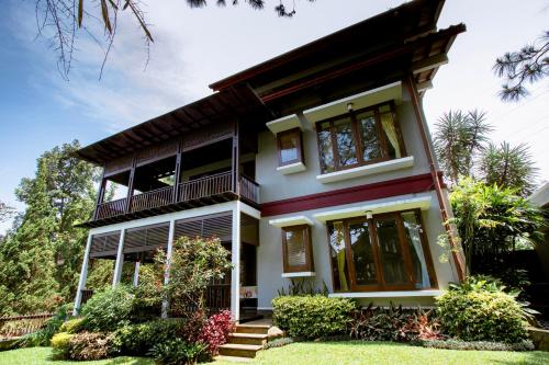 une maison avec un balcon et une cour dans l'établissement Rumah Pelita near Lembang FREE WIFI - Villa Lantera, à Bandung