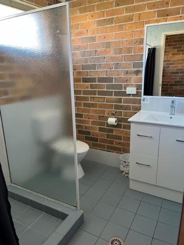 a bathroom with a toilet and a glass shower at Forster Palms Motel in Forster