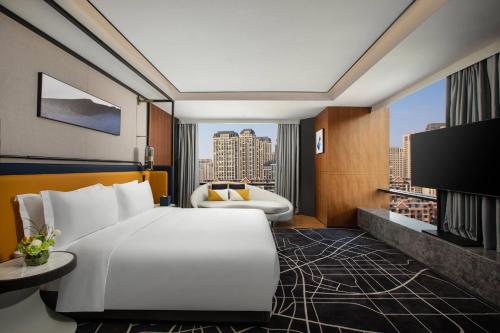 pokój hotelowy z białym łóżkiem i telewizorem w obiekcie voco Hefei Binhu, an IHG Hotel w mieście Hefei