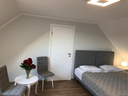 Apartamenti Bocmaņa laukums 2A, Salacgrīva في سالاكغريفا: غرفة نوم بسرير وطاولة مع إناء من الزهور